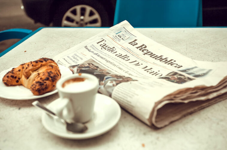 Italiaanse krant op tafel met koffie en croissant