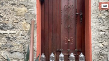 flessen water voor de deur van een huis aan het comomeer