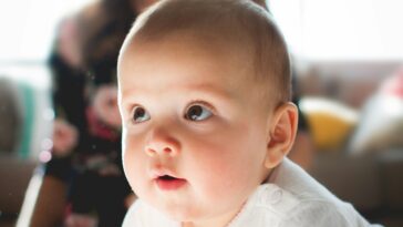 blije baby met moeder op de achtergrond