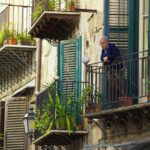 oude man kijkt vanaf balkon in Palermo naar beneden