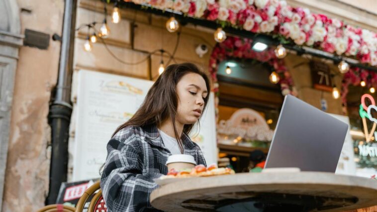Jonge vrouw bij een bar in Rome, werkend op haar laptop