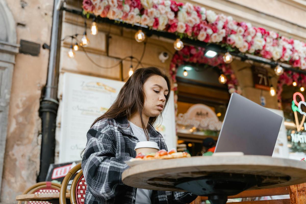 Jonge vrouw bij een bar in Rome, werkend op haar laptop